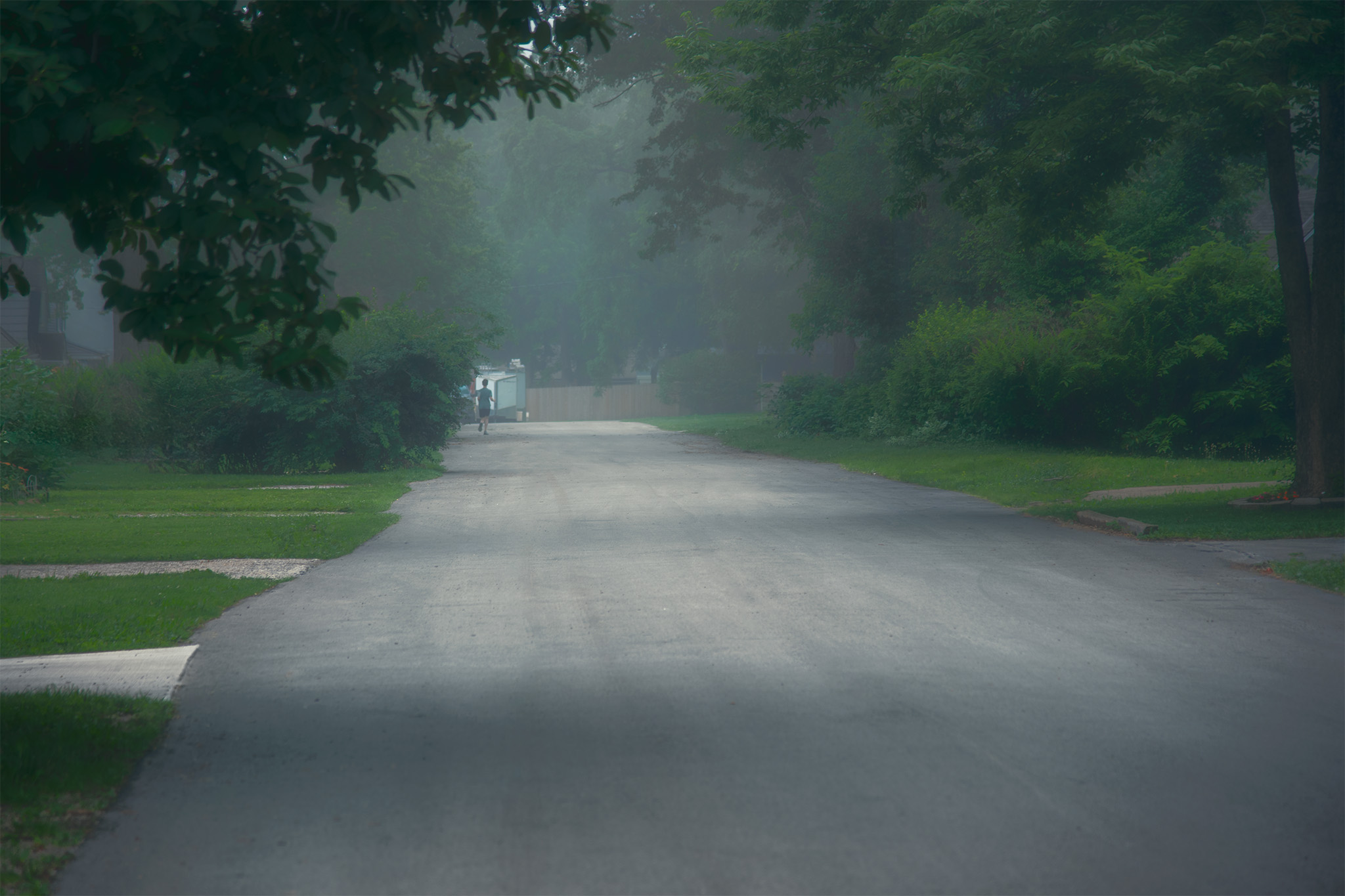 There is a quiet moment that exists between night and day when the world seems to suspend its need to hurry. In Where the Morning Waits, the fog softens the neighborhood into something less defined and more contemplative. Familiar streets become places of possibility rather than destinations, inviting the viewer to slow down and notice what is usually passed without a thought. A solitary figure emerges in the distance, small against the landscape yet inseparable from it. The photograph is not about isolation. It is about relationship. The road, the trees, the mist, and the traveler each shape the meaning of the others. Remove any one element, and the quiet conversation between them disappears. This photograph reflects my ongoing exploration of Mitákuye Oyás'iŋ—the understanding that all things exist in relationship. Rather than documenting a suburban street, I seek to reveal the subtle connections between atmosphere, place, and presence. Light is not simply illumination. Fog is not merely weather. Together they become a veil that encourages us to look beyond the obvious and experience the familiar with renewed attention. My goal is to create photographs that ask the viewer to pause long enough to rediscover wonder in ordinary places. Sometimes the most meaningful landscapes are not found in distant mountains or dramatic coastlines. They exist just beyond our front door, waiting for the right light, the right conditions, and the willingness to truly see. This approach aligns with the broader philosophy expressed in my existing artist statement, emphasizing interconnectedness and our relationship with the world around us.
